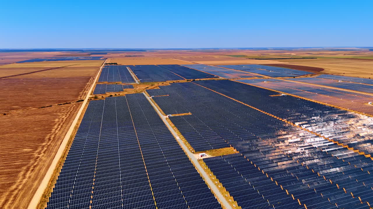 Solar farm installation with photovoltaic panels. Wide solar power plant stretches into the horizon across flat dry terrain