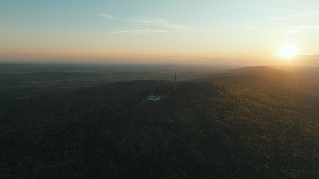 Sunset over a Hilltop with Forest and Building