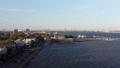 Aerial-rising-dolly-shot-out-over-Charleston-Harbor-along-the-historic-waterfront-during-sunset-in-South-Carolina