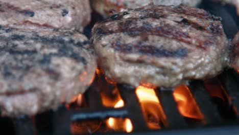 hamburguesas de carne siendo grilladas a la llama en barbacoa