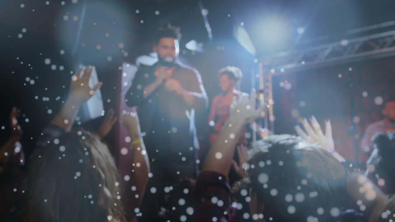 Singer singing music under lights, camera pushing crowd, hands raising red cups clinking toasting