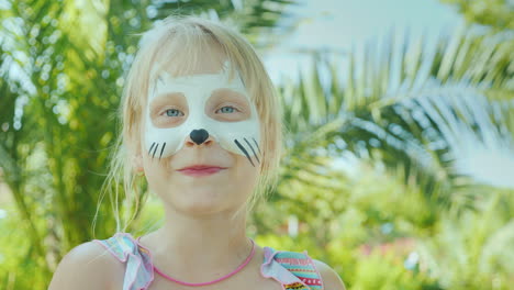 Retrato-De-Una-Niña-Con-Maquillaje-Debajo-De-Un-Gatito-En-Su-Rostro-Contra-El-Telón-De-Fondo-De-Palmeras-En-El-Mar