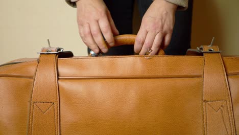 hands holding brown suitcase medium shot