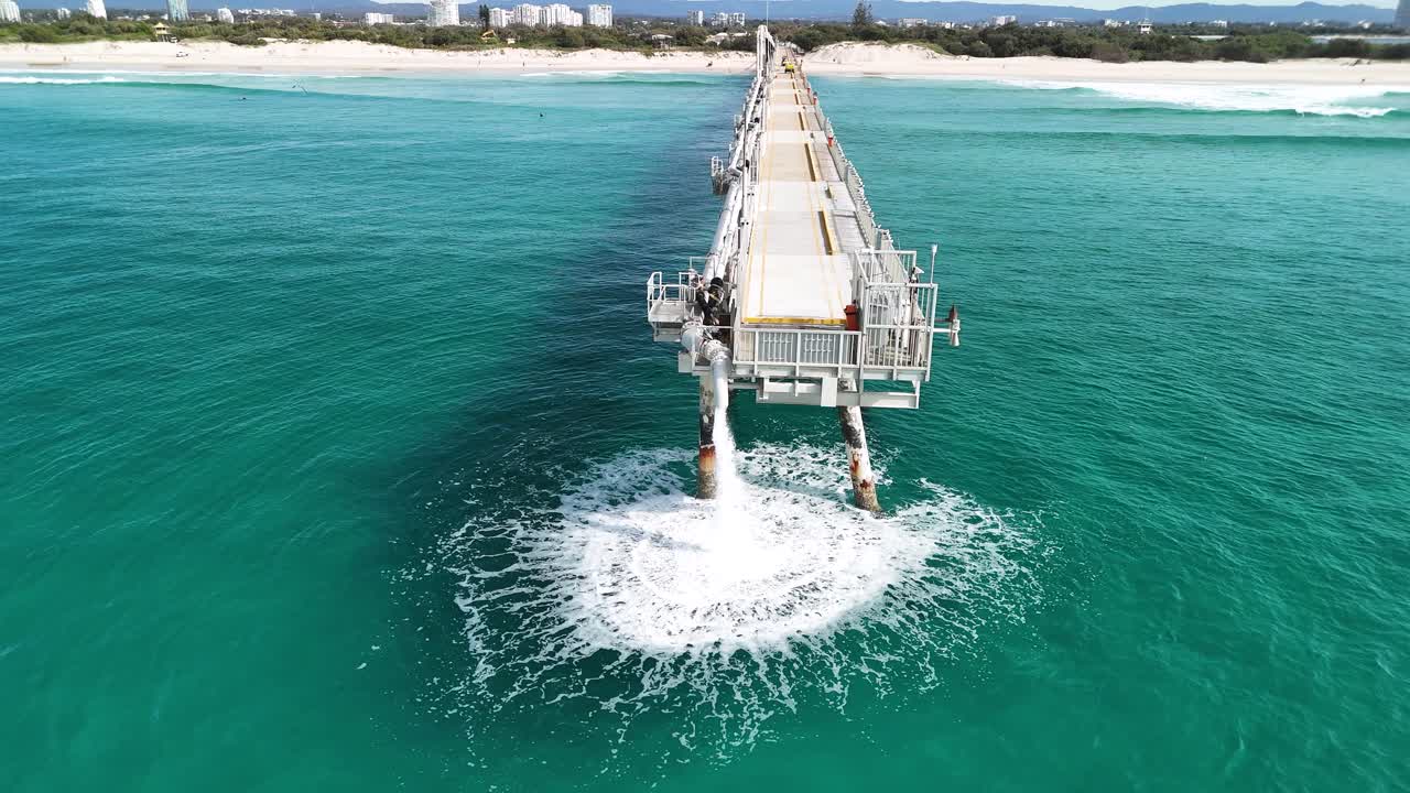 Large industrial structure pumping waste water into the ocean close to a popular holiday beach area. Aerial view