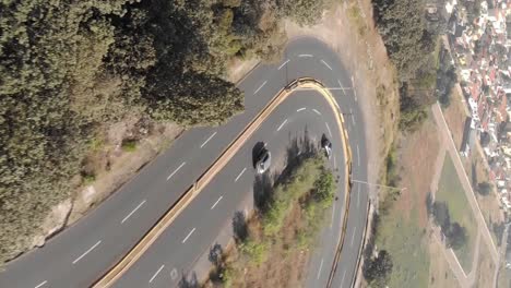 coches conduciendo por una carretera con curvas cerca de la ciudad, vista aérea vertical