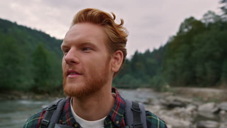 happy man looking around mountain landscape. tourist hiking along river shore