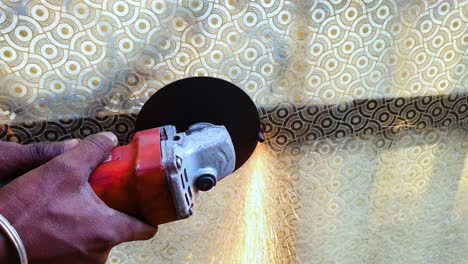 primer plano de un trabajador sosteniendo una hoja de corte circular, cortando clavos de hierro