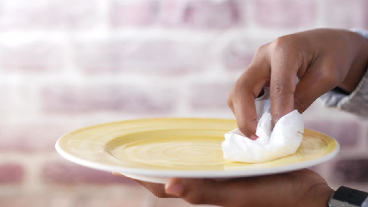 cerca de un joven limpiando una placa con un paño