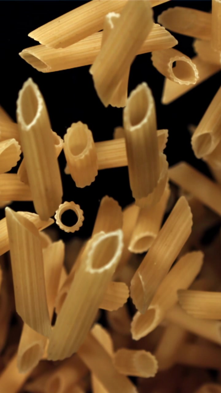 Penne secche che cadono al rallentatore su sfondo nero