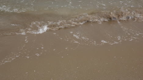 primer plano sobre las suaves olas del mar en la arena amarilla que fluye pacíficamente