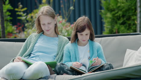 Two-girls-read-books,-sit-on-a-garden-swing-in-the-backyard-of-the-house