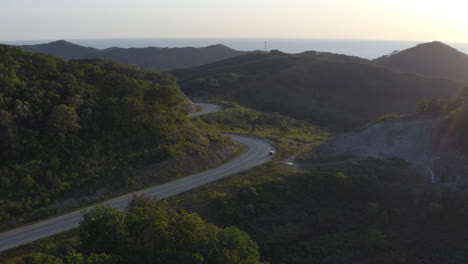 camino serpenteante en las montañas con camión estacionado en el lado de la carretera al atardecer