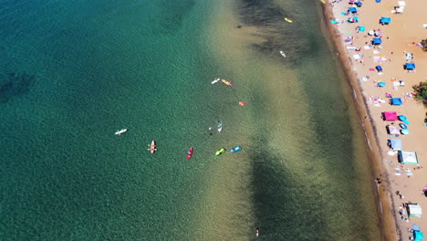 aerial top view of people relaxing on a sandy beach next to crystal clear water in lake tahoe