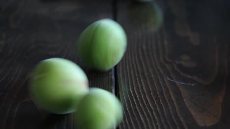 a video of japanese apricot rolling on a wooden table.