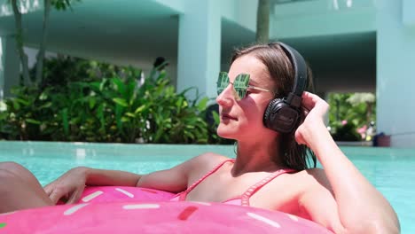 chica en el círculo inflable en la piscina y escucha música en la tienda.