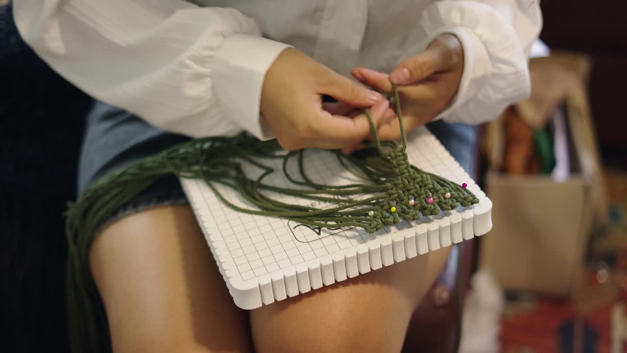 Close-up of hands crafting macrame on a board