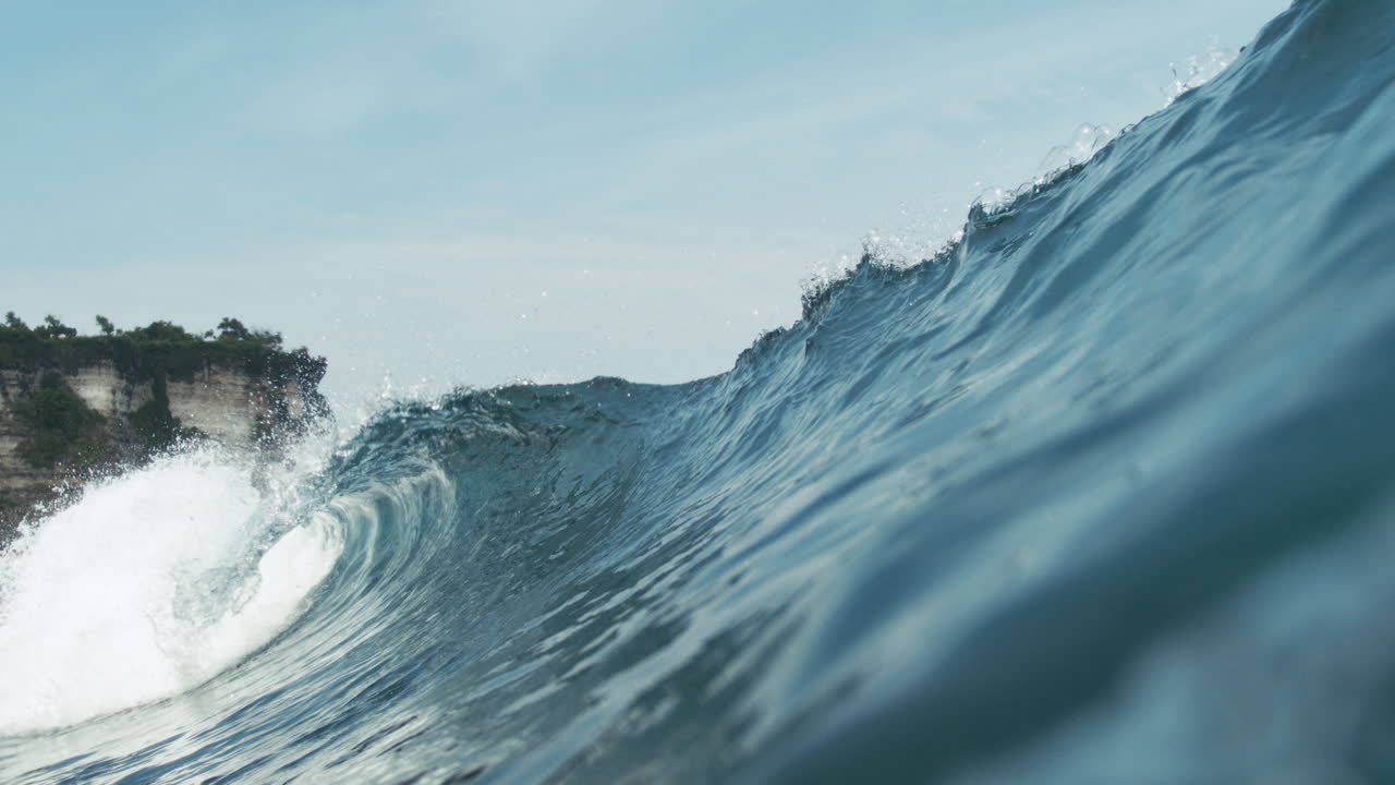 Slow motion wave begins to break over open ocean with texture and depth