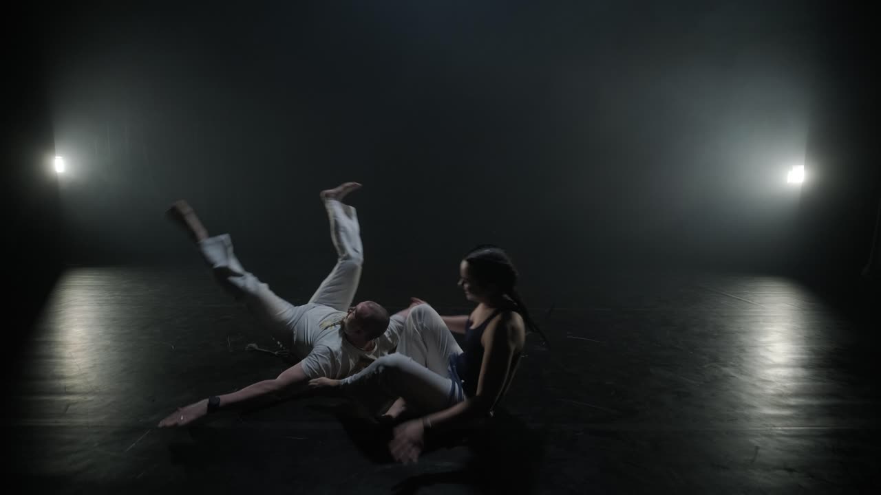 Lottatori di Capoeira che eseguono mosse dinamiche sul palco. Arti marziali, danza e acrobazie in azione. Atleti a torso nudo che mostrano forza, flessibilità e tecnica sotto i riflettori
