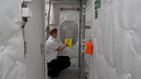 captain use hands to signal entry forbidden, tanks in ships engine room area