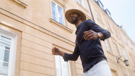 feliz afro caribeño hombre con sombrero bailando en el centro