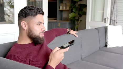 Relaxing on couch, man using smartphone for voice command in living room