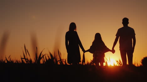 parents with the child stand in a picturesque place admiring the sunrise holding hands happy family