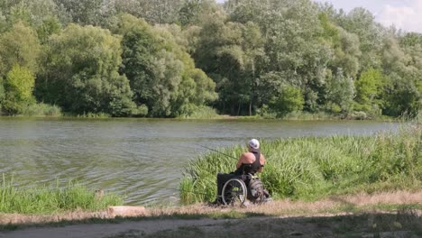 man with disabilities fishing at a lake. wheelchair. camping. summertime