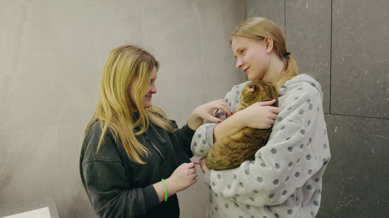 Sisters cuddling a cat in the bathroom