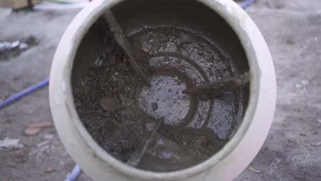 close up of concrete mixer spinning with cement and rocks inside in slow motion