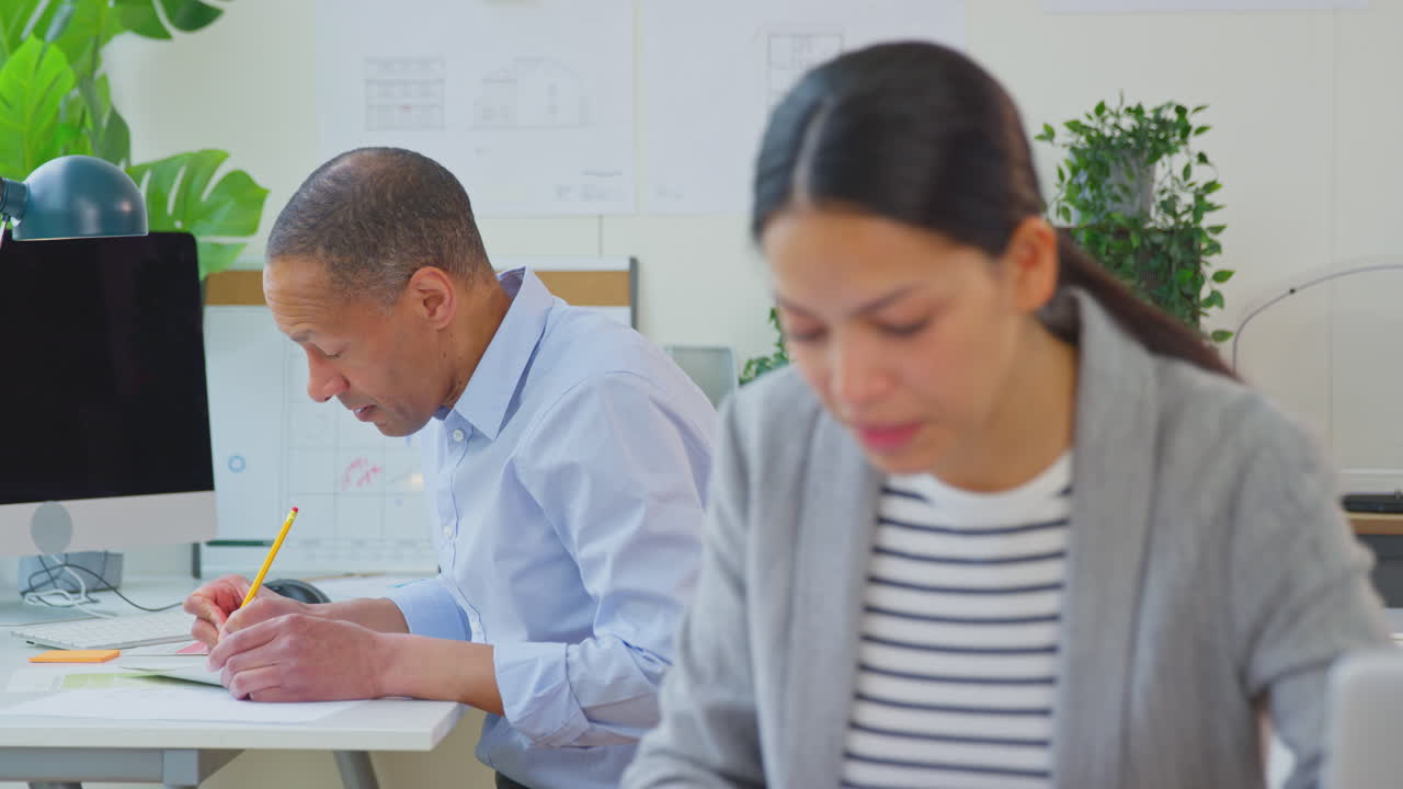 arquitectos masculinos y femeninos trabajando en la oficina en escritorios en planes para nuevos edificios