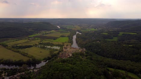 Aerial-footage-drone-fly-above-of-Beynac-et-cazenac-france-medieval-small-stone-village-in-the-dordogne-forest-historical-site-at-sunset