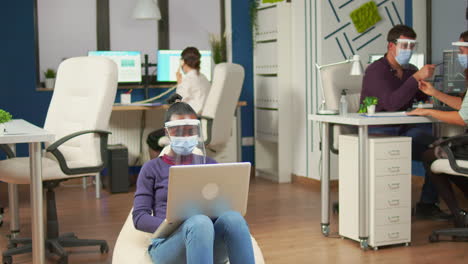 African-employee-with-visor-sitting-on-armchair-in-middle-of-office