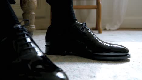 slow motion shot of a groom's shiny black shoes ready for his wedding ceremony