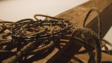 religious concept shot with crown of thorns rope and wooden cross in pool of light