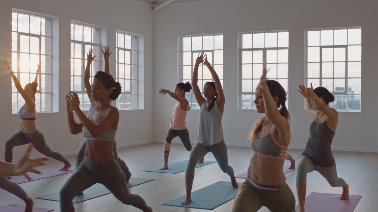 전사 포즈를 연습하는 건강한 여성의 요가 수업은 일출 시 그룹 명상 교육 운동 자세를 이끄는 피트니스 스튜디오 강사에서 운동을 즐기고 있습니다.