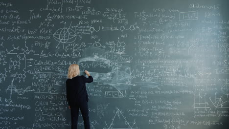 woman writing equations on a chalkboard