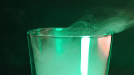 close-up of a green smoke pouring and flowing from a glass