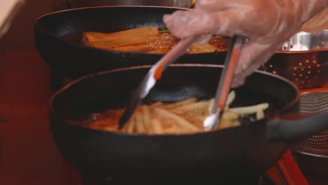 a woman cooks french fries in a frying pan at a night market in palau