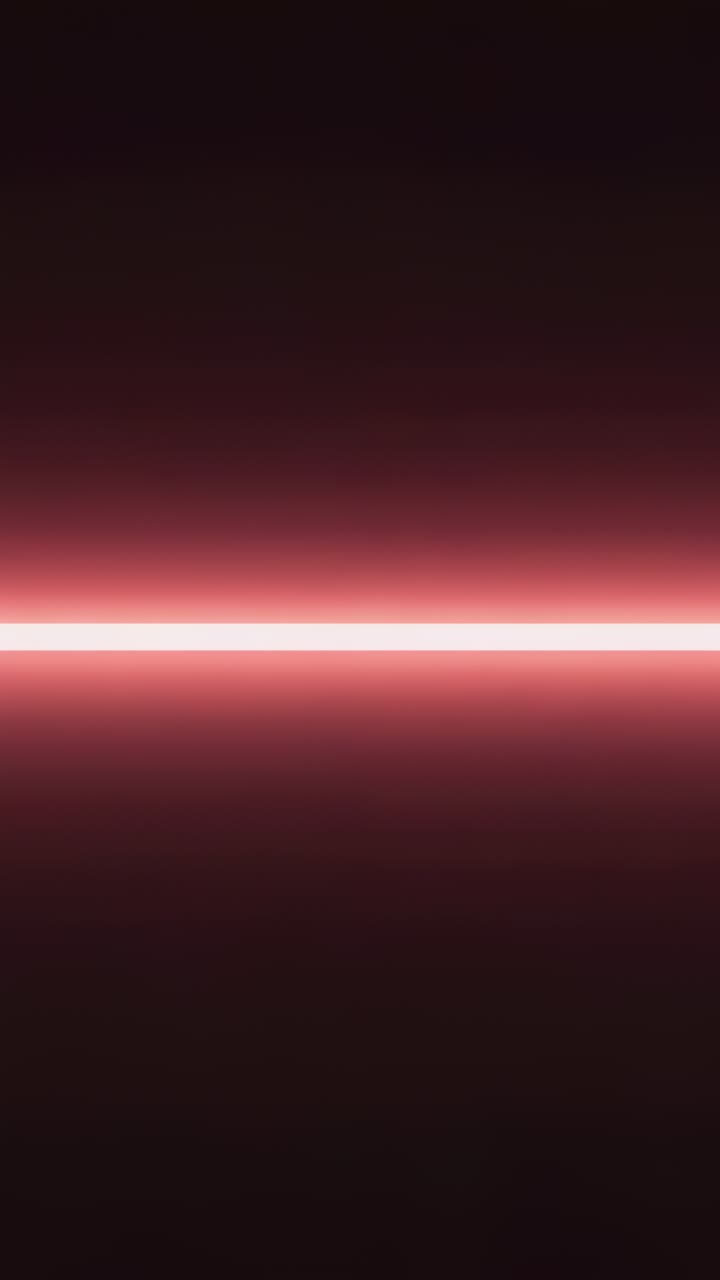 Vertical video: Pulsating horizontal neon-pink light bar emitting soft gradient glow in dark stage