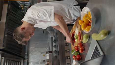 chef cutting vegetables while watching video tutorial