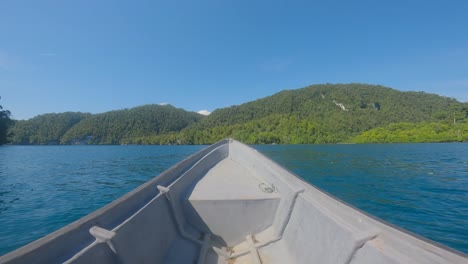 bow of boat sailing toward island on kali biru blue river of raja ampat archipelago in indonesia