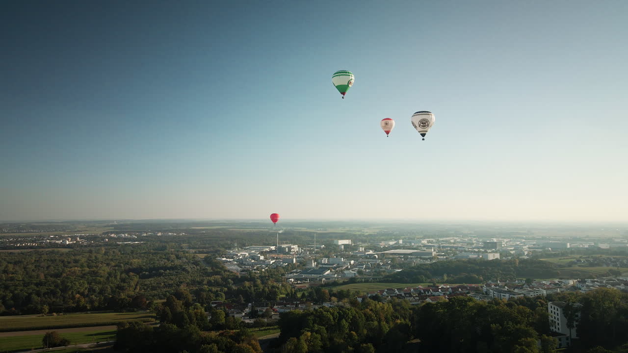 Ulm şehir silüeti üzerinde, berrak mavi gökyüzünde süzülen sıcak hava balonlarıyla çekilmiş akıcı 4K drone ileri uçuşu, turizm, etkinlikler ve kurumsal b-roll çekimleri için ideal