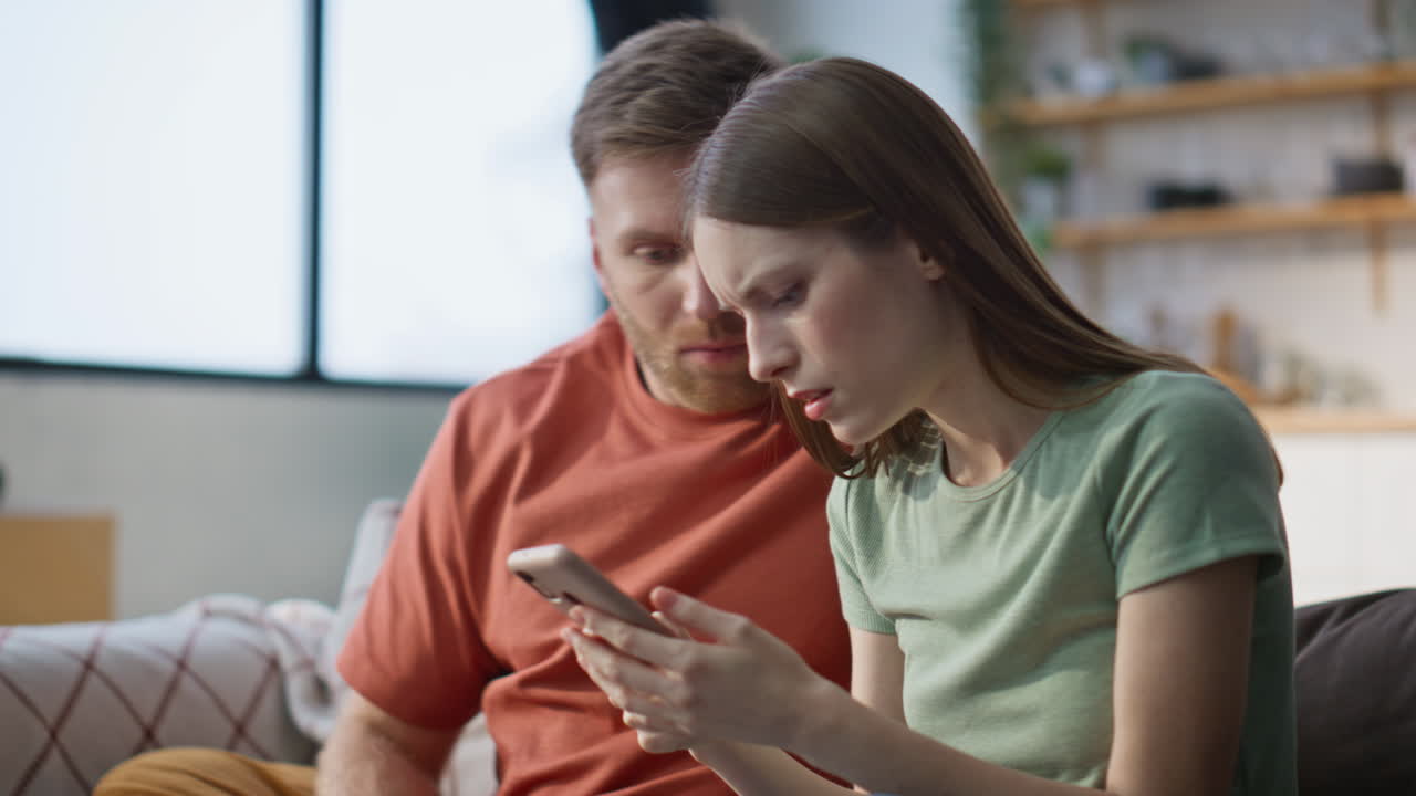 Troubled family receiving message on mobile phone in living room home closeup