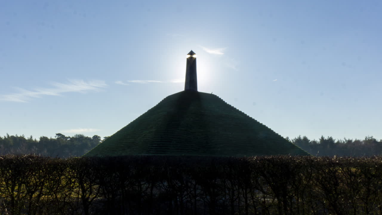 Medium shot Time lapse of sun appearing behind obelisk on Austerlitz Pyramid. The Piramide van Austerlitz is a monument built in 1804 as a tribute to Napoleon Bonaparte.
