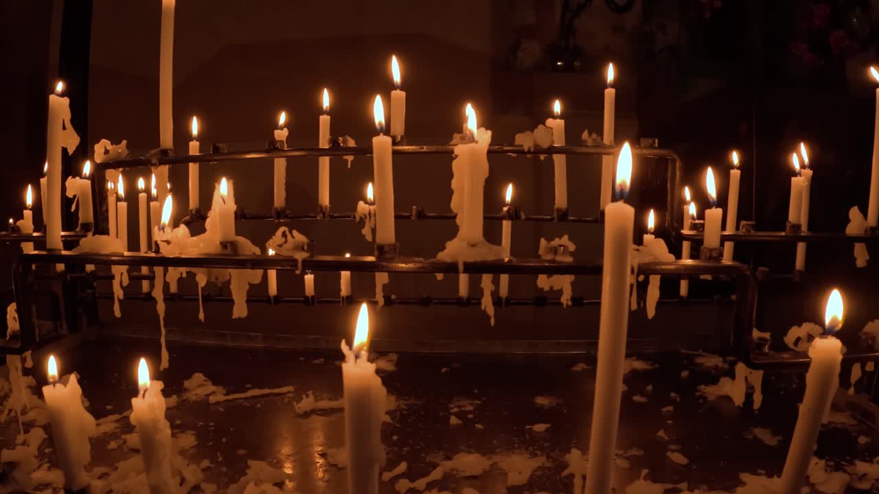 Close-up handheld shot of melted church candles in dark room