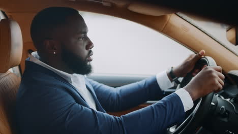 side view man sitting behind steering wheel at car. african man dancing at car