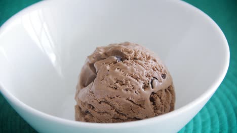 scoop of chocolate ice cream being dropped inside a white bowl