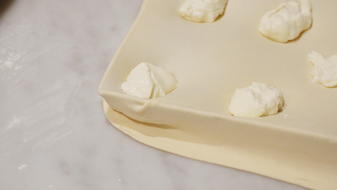 Man preparing focaccia di Recco, a Ligurian dish, shaping the dough and adding cheese