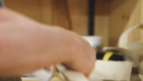 Close-up-footage-of-hands-folding-long-strip-of-parchment-paper-on-timber-desk