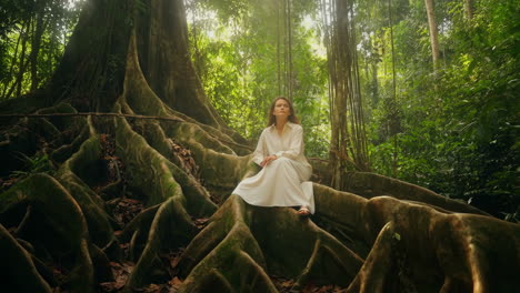 Woman sitting on ancient tree roots in a tropical forest